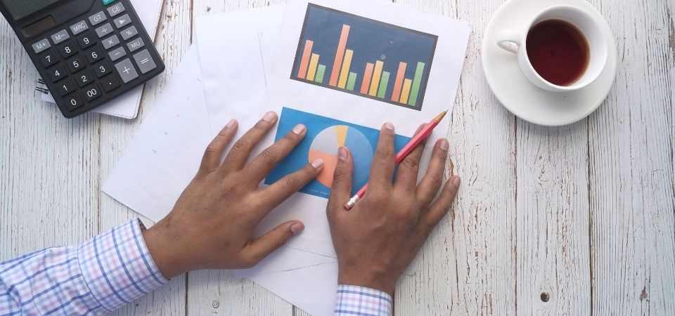 işimi nasıl büyütebilirim masada oturan adam kağıt üstündeki analizleri inceliyor